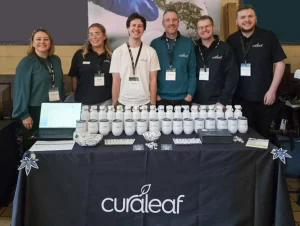 Six of the Curaleaf team behind a conference stand table